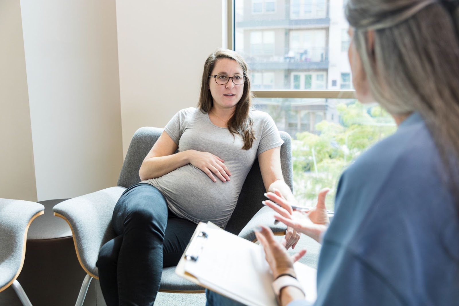a pregnant woman is speaking to her midwife at her antenatal appointment