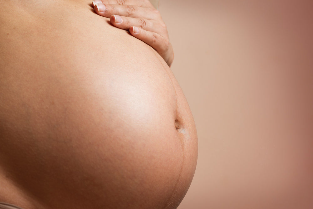 A pregnant woman with a hand on her tummy. She has antenatal care from her midwife. 