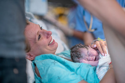 A newborn baby is held to its mother’s bare chest to practise skin-to-skin contact.