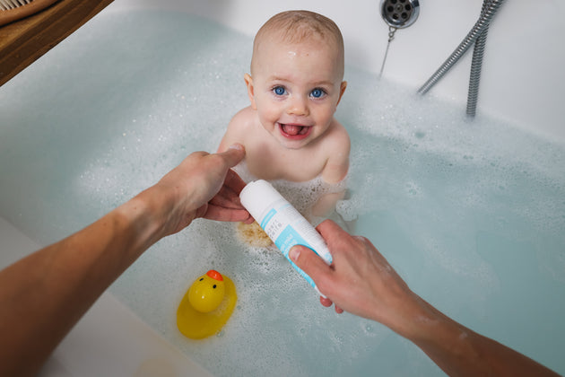 A baby in a bath tub about to be cleaned with My Expert Midwife Mega Mild Cleansing Wash.