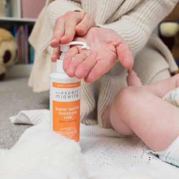 A mother pumps My Expert Midwife Super Settle Moisture Milk into her hand, ready to moisturise her baby's skin.