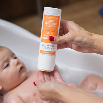 A mother squeezing My Expert Midwife Super Settle Cleansing Wash into her hands ready to wash her baby in the bath.